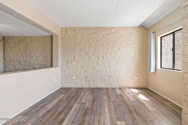 empty room with a textured ceiling and wood finished floors