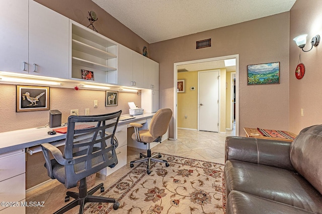 home office with visible vents, baseboards, a textured ceiling, and built in desk