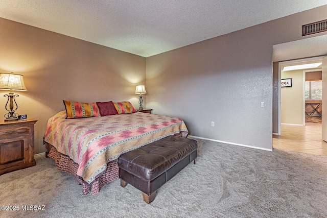 carpeted bedroom with visible vents, a textured ceiling, baseboards, and a textured wall