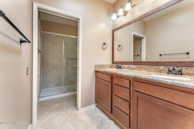 full bathroom with double vanity, a textured wall, a marble finish shower, and a sink