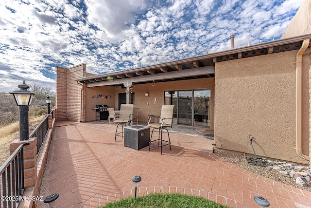 view of patio with area for grilling and a fire pit