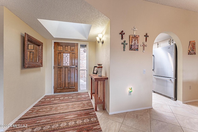 foyer with baseboards, arched walkways, and a textured ceiling