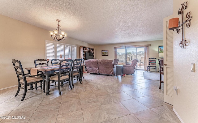 dining space with a textured ceiling, baseboards, and an inviting chandelier