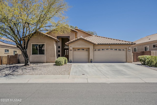 view of front of house featuring driveway, fence, a garage, a tile roof, and stucco siding