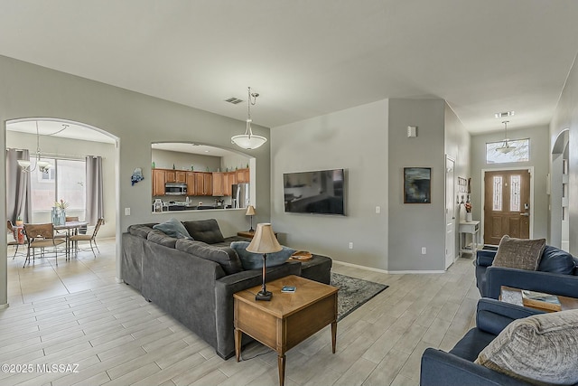 living room with arched walkways, visible vents, and light wood-style floors