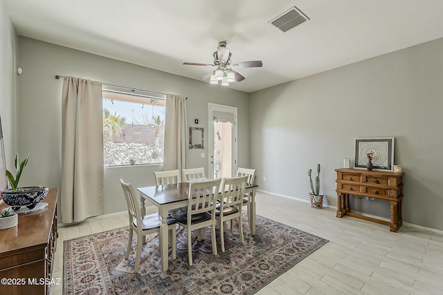 dining room featuring light wood finished floors, baseboards, ceiling fan, and visible vents