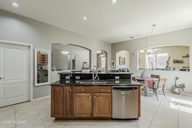kitchen with arched walkways, a sink, light tile patterned flooring, and dishwasher