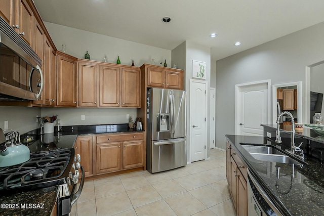 kitchen featuring a sink, brown cabinets, appliances with stainless steel finishes, and dark stone countertops