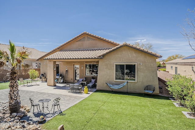 back of property featuring fence, stucco siding, a tiled roof, and a yard