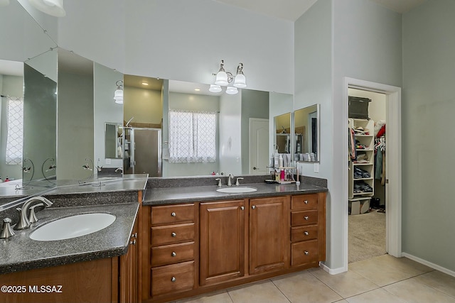 full bathroom with a shower stall, tile patterned floors, double vanity, and a sink