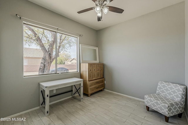 living area with light wood finished floors, baseboards, and a ceiling fan