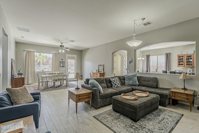 living area with arched walkways, light wood-style flooring, visible vents, and ceiling fan