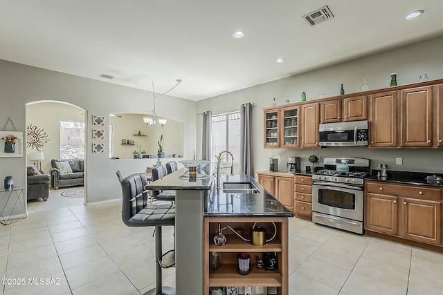 kitchen with a kitchen bar, open shelves, a sink, visible vents, and appliances with stainless steel finishes