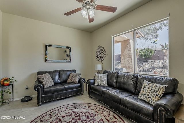 living area featuring baseboards, light wood-type flooring, and a ceiling fan