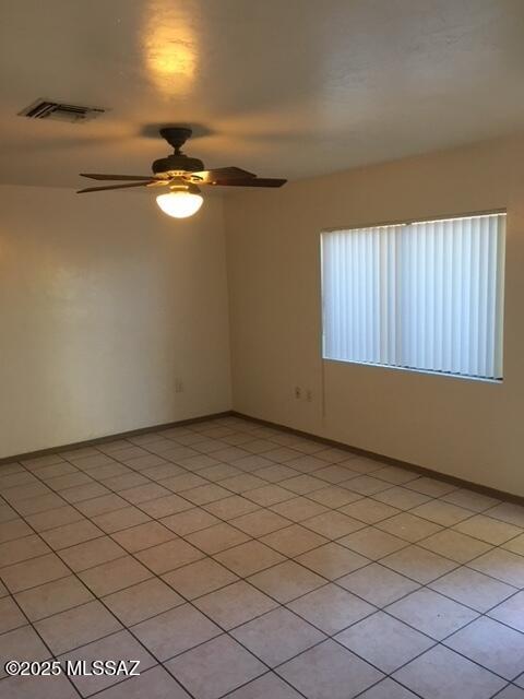 unfurnished room featuring light tile patterned floors, visible vents, a ceiling fan, and baseboards