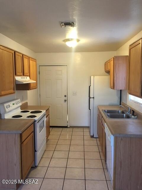 kitchen featuring visible vents, light tile patterned floors, range hood, white appliances, and a sink