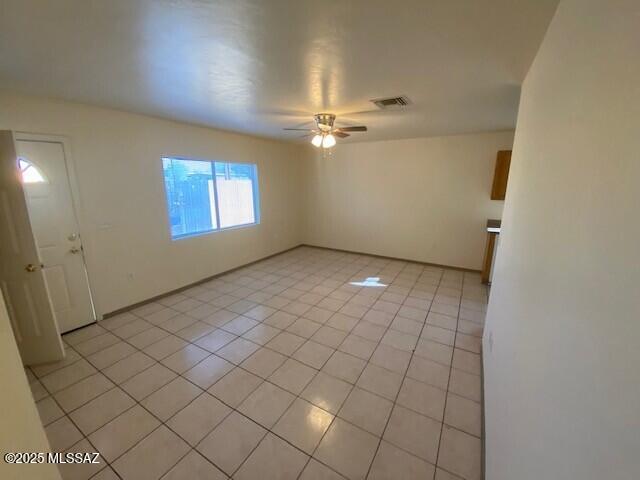 empty room with light tile patterned floors, visible vents, and ceiling fan