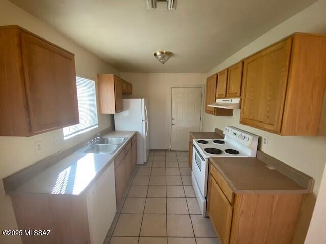 kitchen featuring visible vents, under cabinet range hood, brown cabinetry, white appliances, and a sink