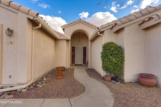 property entrance with a tiled roof and stucco siding