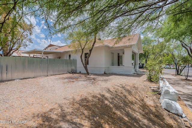 rear view of house featuring stucco siding and fence