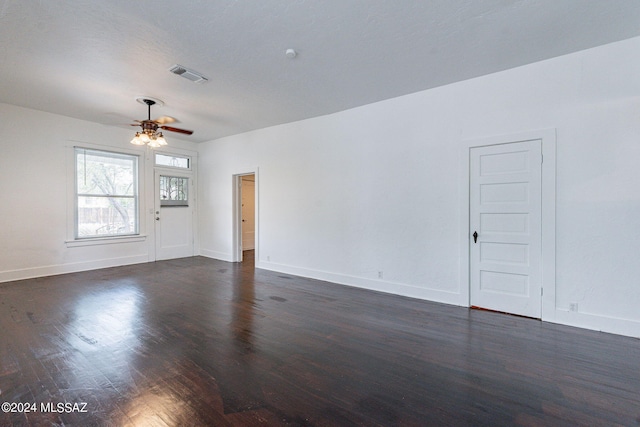 empty room with dark wood finished floors, baseboards, visible vents, and ceiling fan