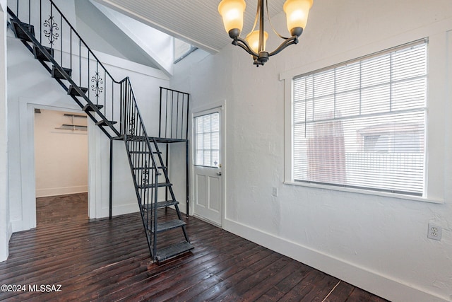 interior space featuring a notable chandelier, dark wood-style floors, baseboards, stairs, and vaulted ceiling