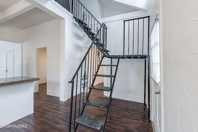 stairs featuring a high ceiling, baseboards, and hardwood / wood-style flooring