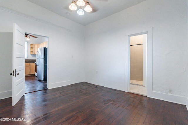 unfurnished bedroom featuring dark wood-style floors, ensuite bathroom, freestanding refrigerator, and baseboards