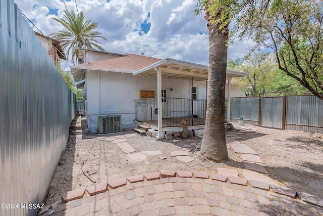 rear view of house featuring cooling unit, a shingled roof, stucco siding, and fence