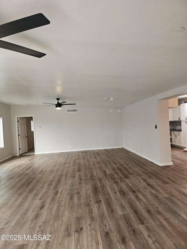 unfurnished living room with wood finished floors, baseboards, ceiling fan, and visible vents