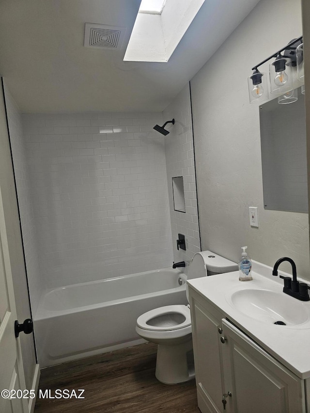 bathroom with visible vents, a skylight, toilet, wood finished floors, and vanity