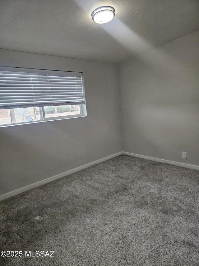 carpeted spare room featuring baseboards