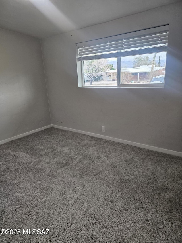 spare room featuring carpet flooring and baseboards