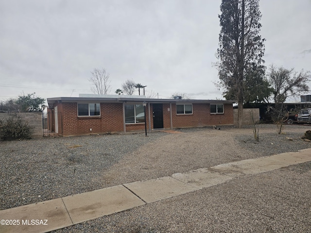 ranch-style house featuring brick siding and fence