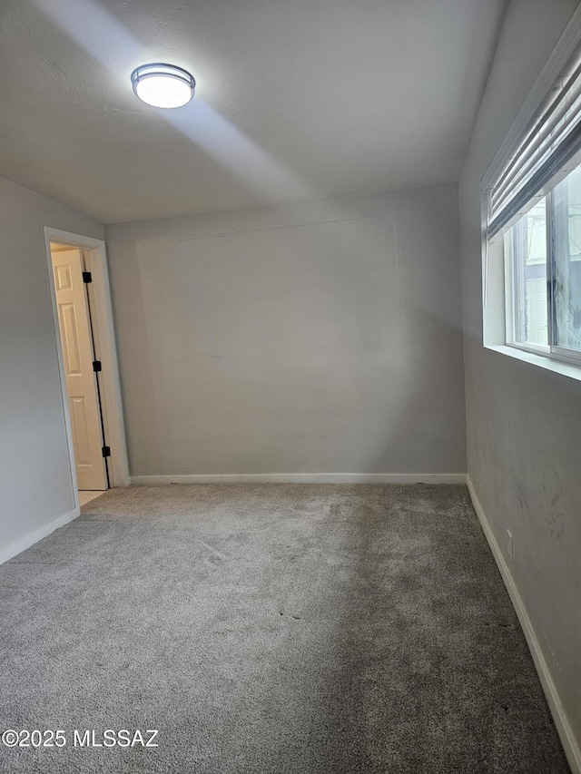 carpeted spare room featuring baseboards