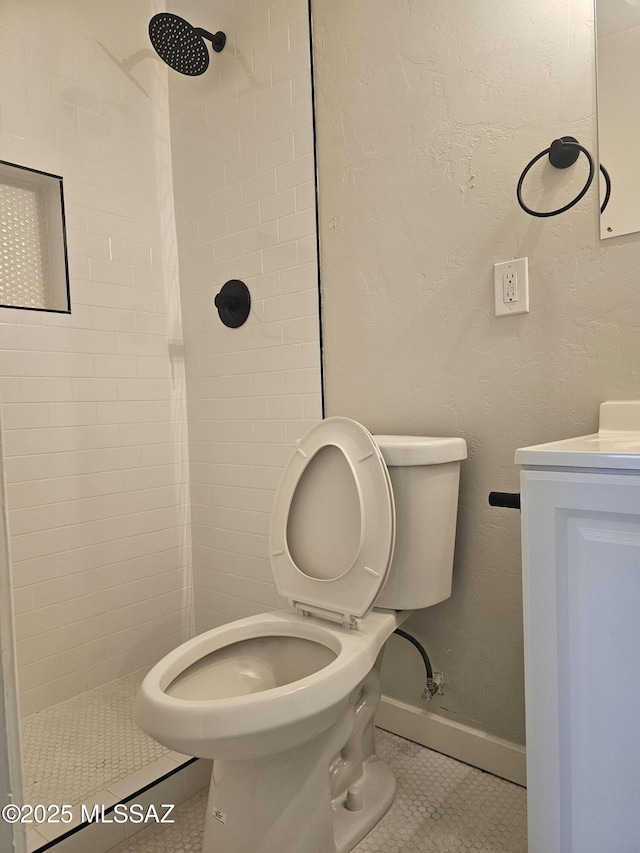 bathroom featuring toilet, tile patterned flooring, and tiled shower