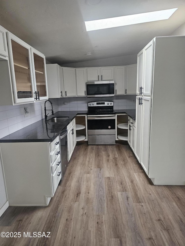 kitchen with white cabinets, a sink, stainless steel appliances, and dark countertops