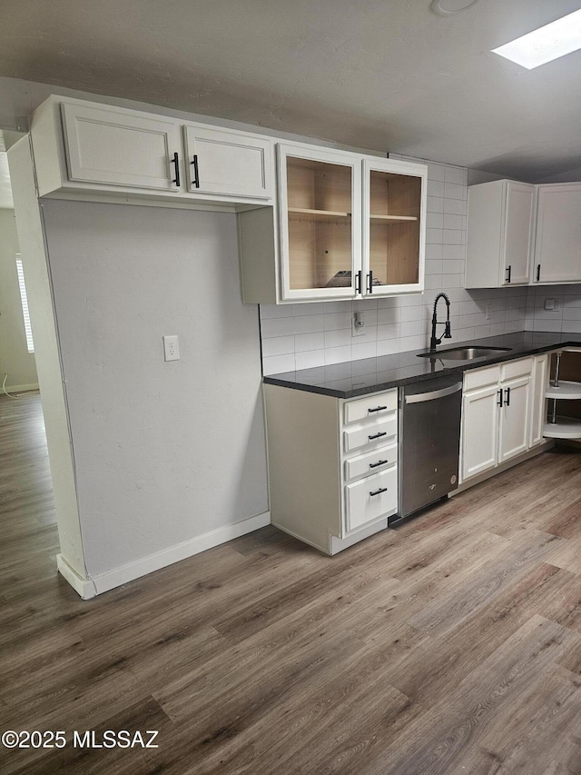 kitchen featuring dishwasher, wood finished floors, dark countertops, and decorative backsplash