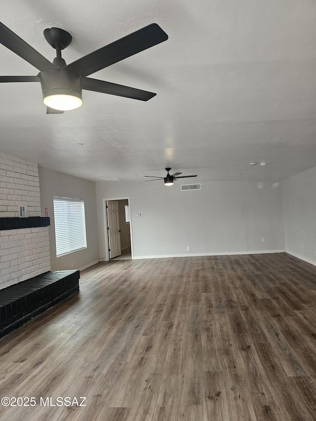 unfurnished living room with a fireplace, baseboards, ceiling fan, and wood finished floors