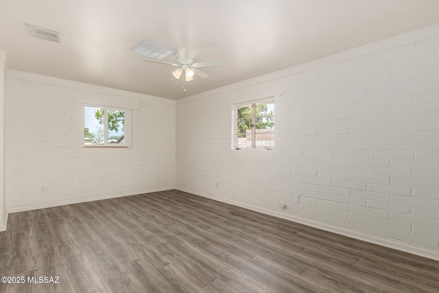 spare room featuring visible vents, plenty of natural light, dark wood-style floors, and ceiling fan