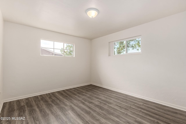 empty room featuring dark wood-type flooring and baseboards