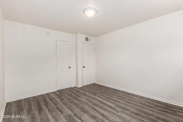 spare room with dark wood-type flooring, baseboards, and visible vents