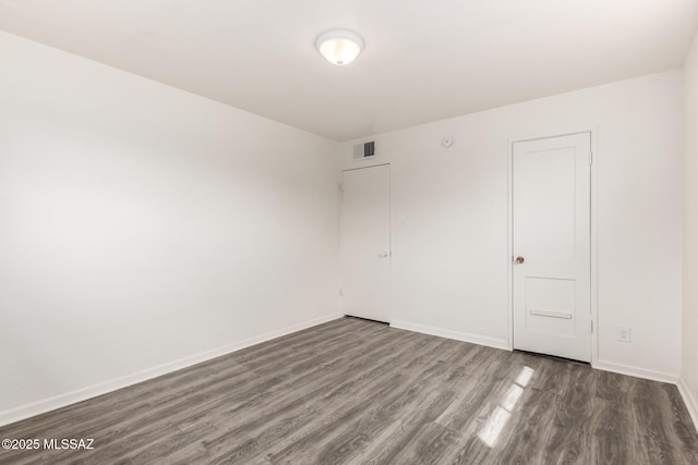 spare room featuring visible vents, baseboards, and wood finished floors