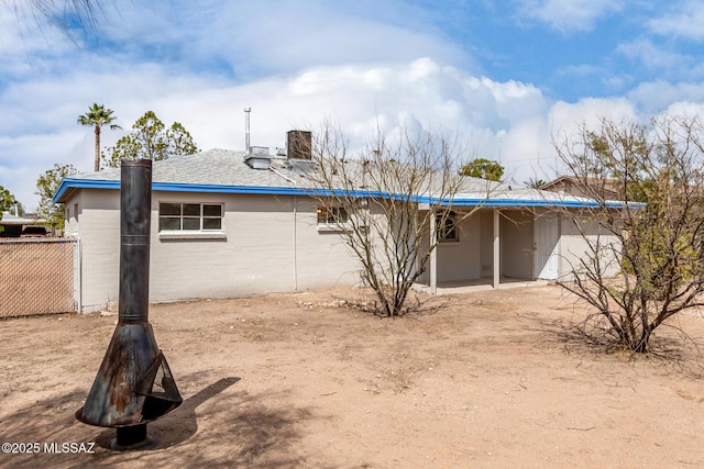 back of house featuring a chimney and fence