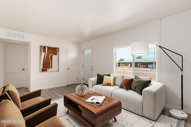 living room featuring light wood-style flooring, baseboards, and visible vents