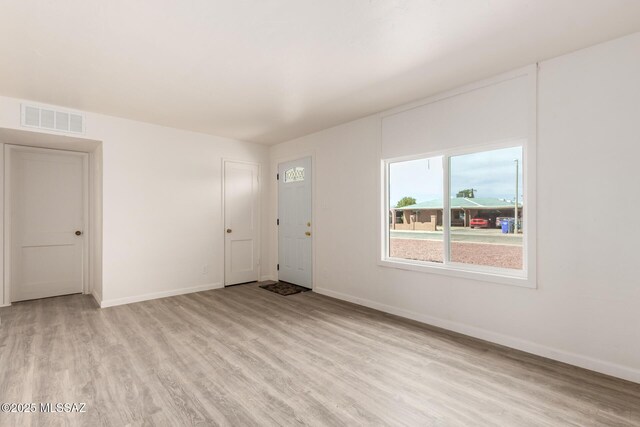 unfurnished room featuring light wood-type flooring, visible vents, and baseboards