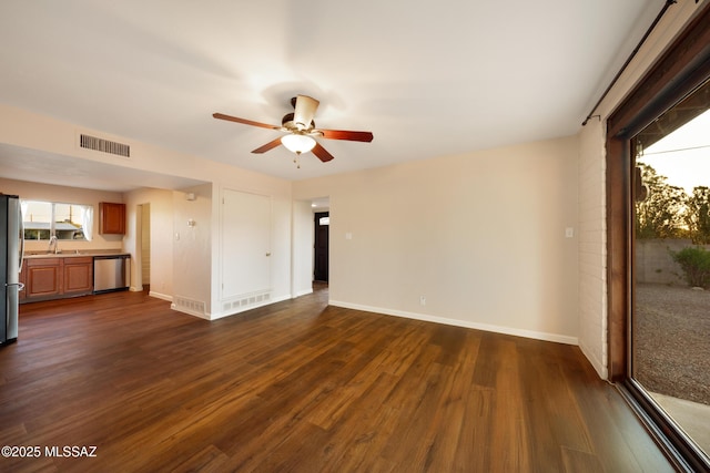 unfurnished living room with ceiling fan, dark wood finished floors, baseboards, and a sink