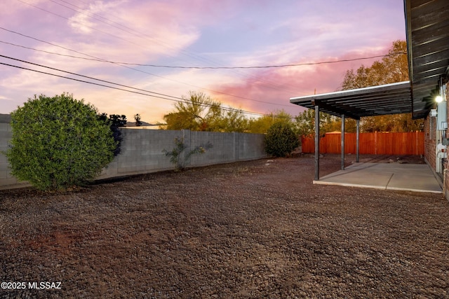 yard at dusk featuring a fenced backyard and a patio area