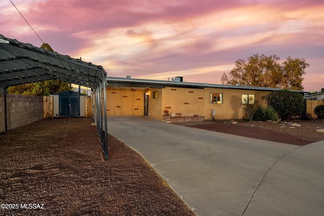 view of front of house featuring a storage unit, fence, an outbuilding, and concrete driveway