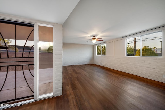 spare room with brick wall, a ceiling fan, and wood finished floors